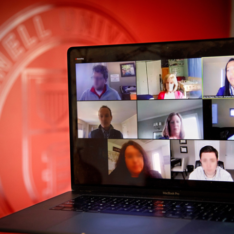 Laptop in front of the Cornell Logo. A video meeting is on the screen.